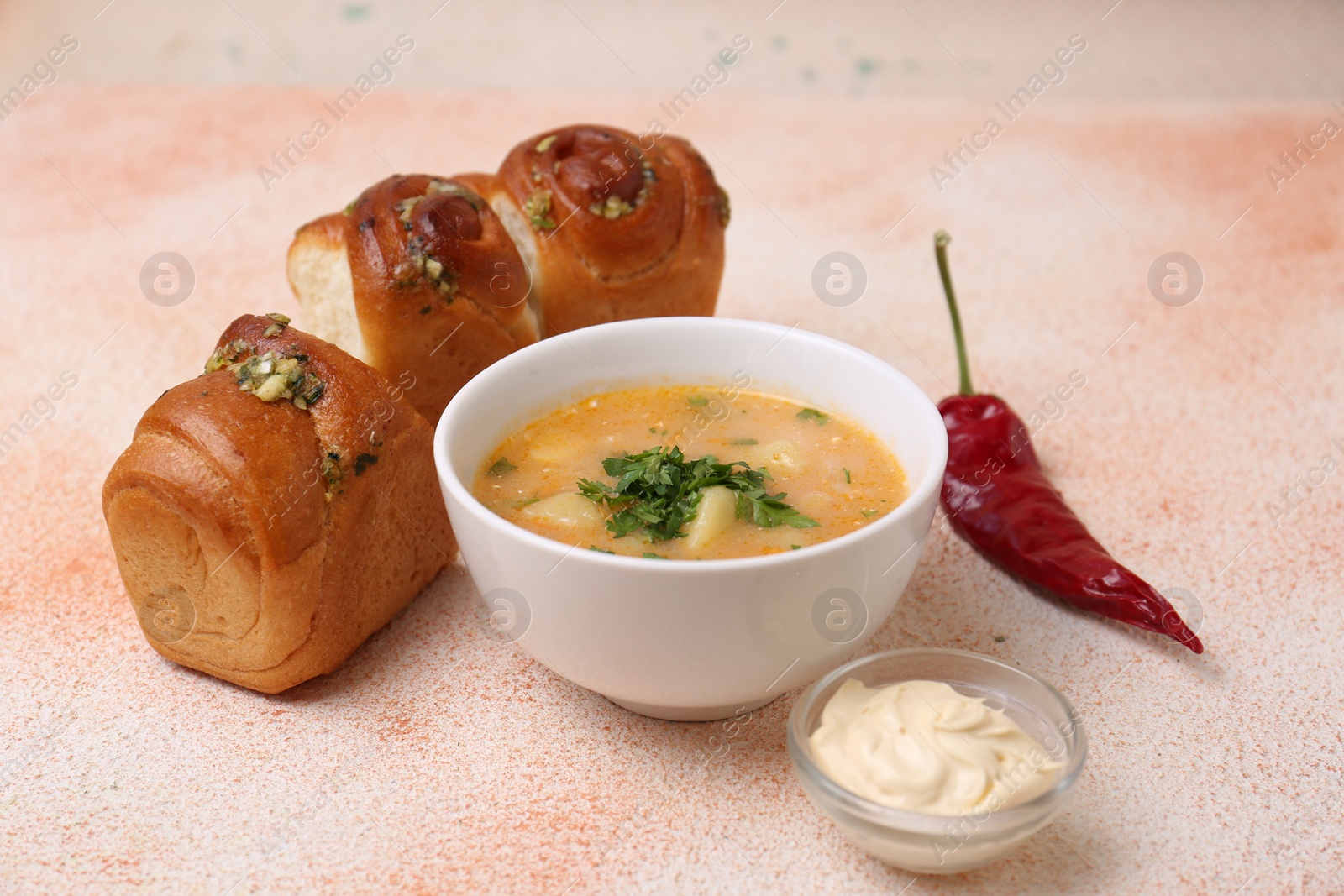 Photo of Delicious borsch served with pampushky on color textured table. Traditional Ukrainian cuisine