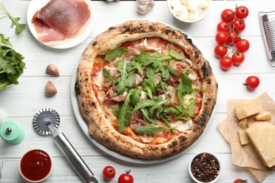 Tasty pizza with meat and arugula on white wooden table, flat lay