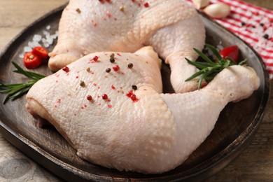 Photo of Raw chicken leg quarters and ingredients on wooden table, closeup