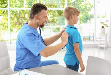 Male medical assistant examining child in clinic