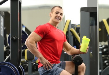 Athletic young man with protein shake in gym