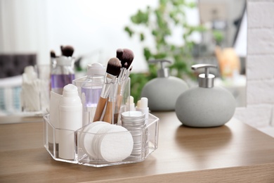 Photo of Organizer with cosmetic products on wooden table in bathroom