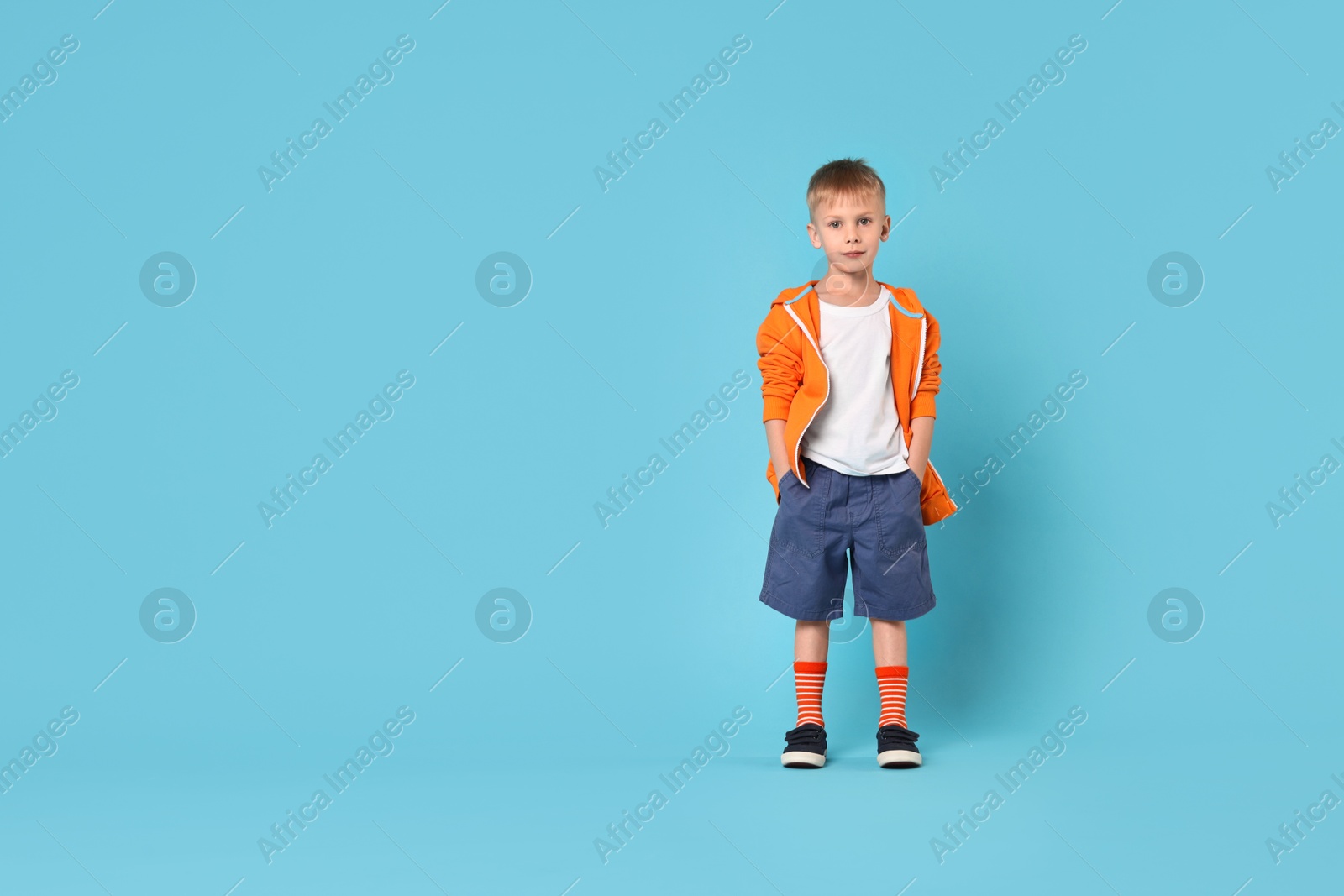 Photo of Happy little boy dancing on light blue background. Space for text