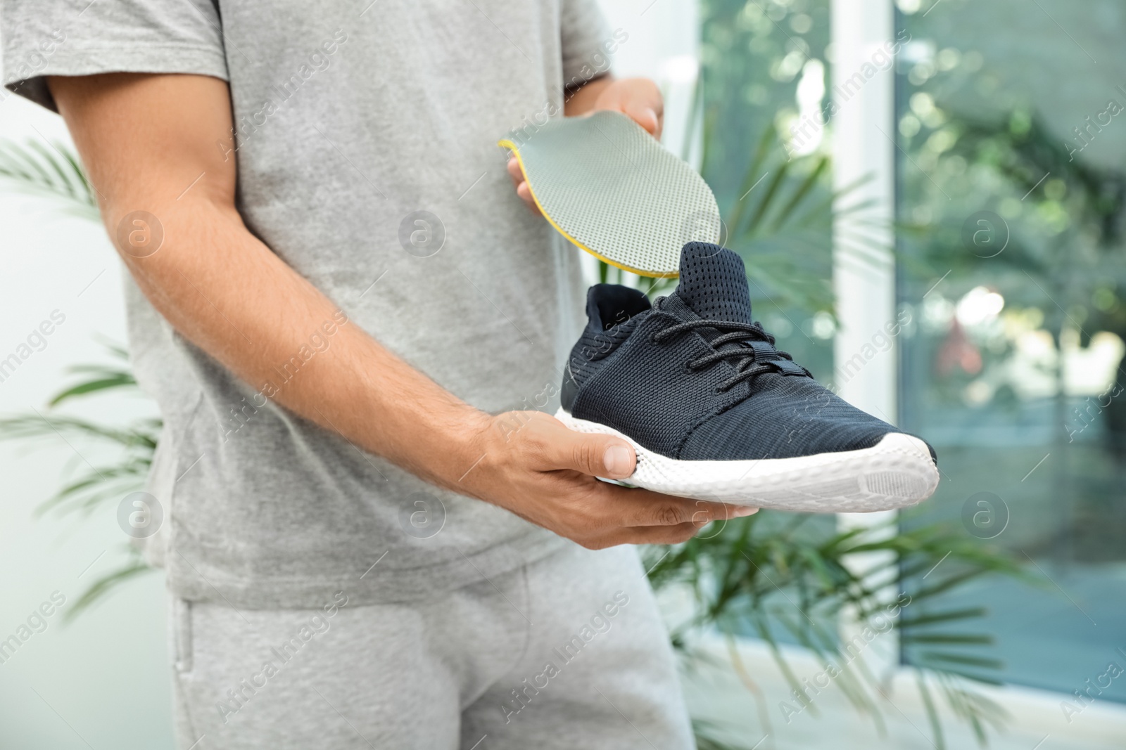 Photo of Man putting orthopedic insole into shoe indoors, closeup. Foot care