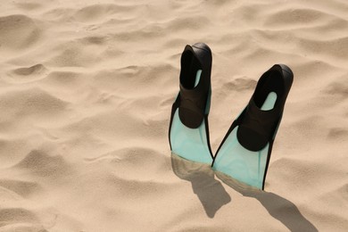 Pair of turquoise flippers on sand. Space for text