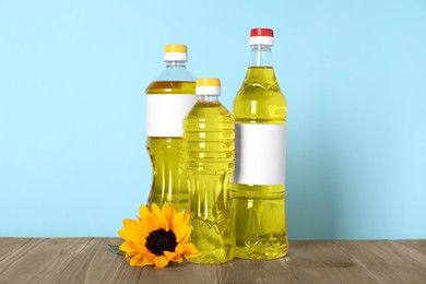 Photo of Bottles of cooking oil and sunflower on wooden table