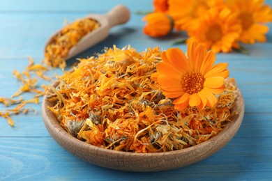 Photo of Plate of dry calendula flowers on light blue wooden table, closeup