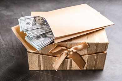 Photo of Envelope with dollar bills and gift box on grey stone table