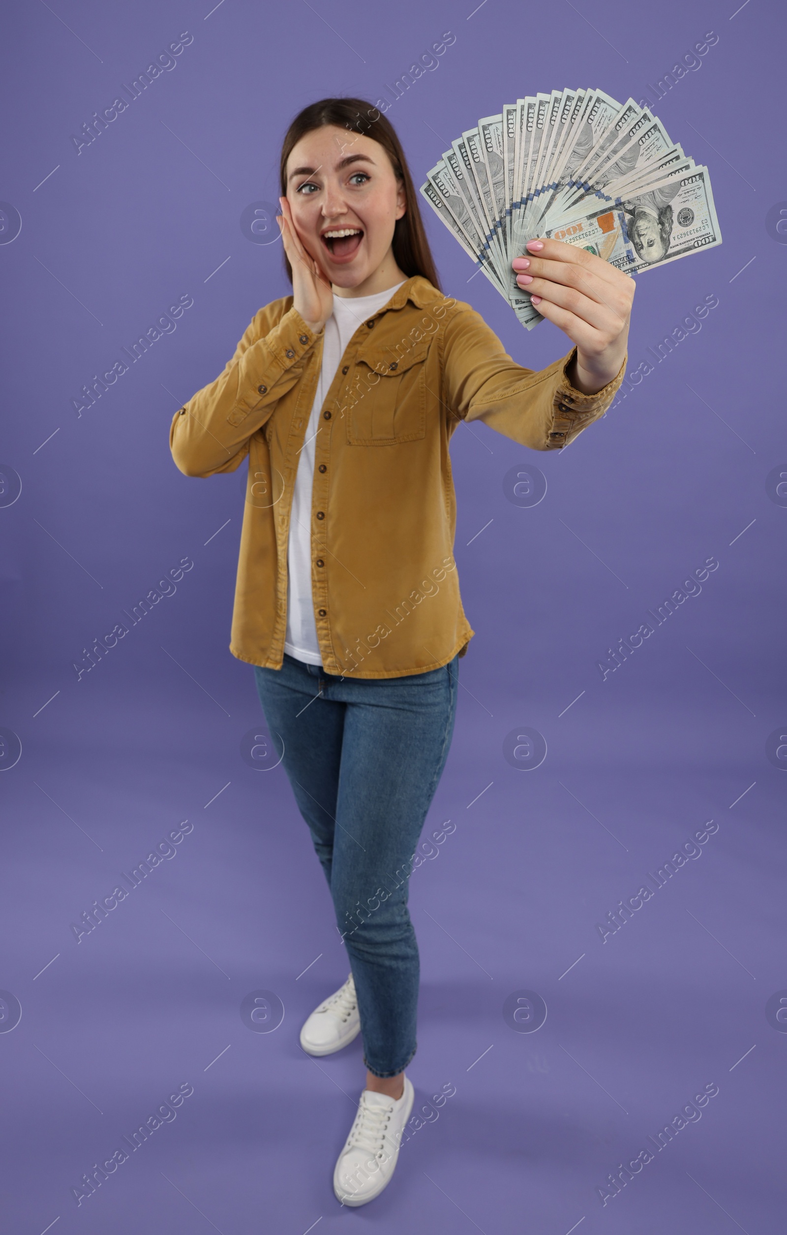 Photo of Happy woman with dollar banknotes on purple background