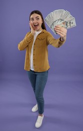 Happy woman with dollar banknotes on purple background