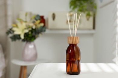 Aromatic reed air freshener on white table in room. Space for text
