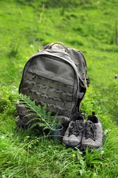 Photo of Backpack and hiking boots in green mountain valley. Summer camping