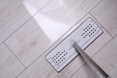 Photo of Cleaning dirty parquet floor with mop indoors, top view. Space for text