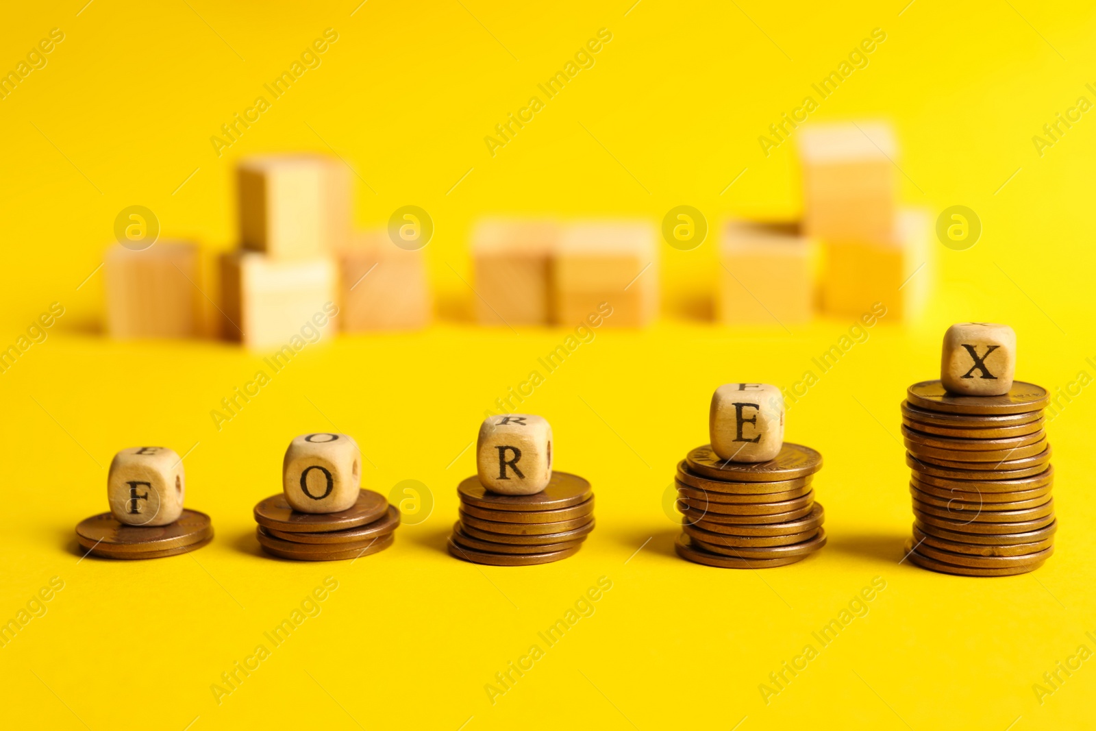 Photo of Word Forex made of wooden cubes with letters on stacked coins against yellow background