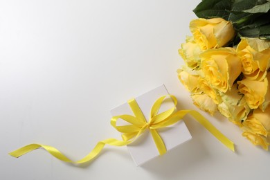 Photo of Beautiful bouquetyellow roses and gift box on white background, flat lay. Space for text