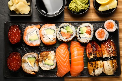 Photo of Set of delicious sushi rolls on black table, flat lay