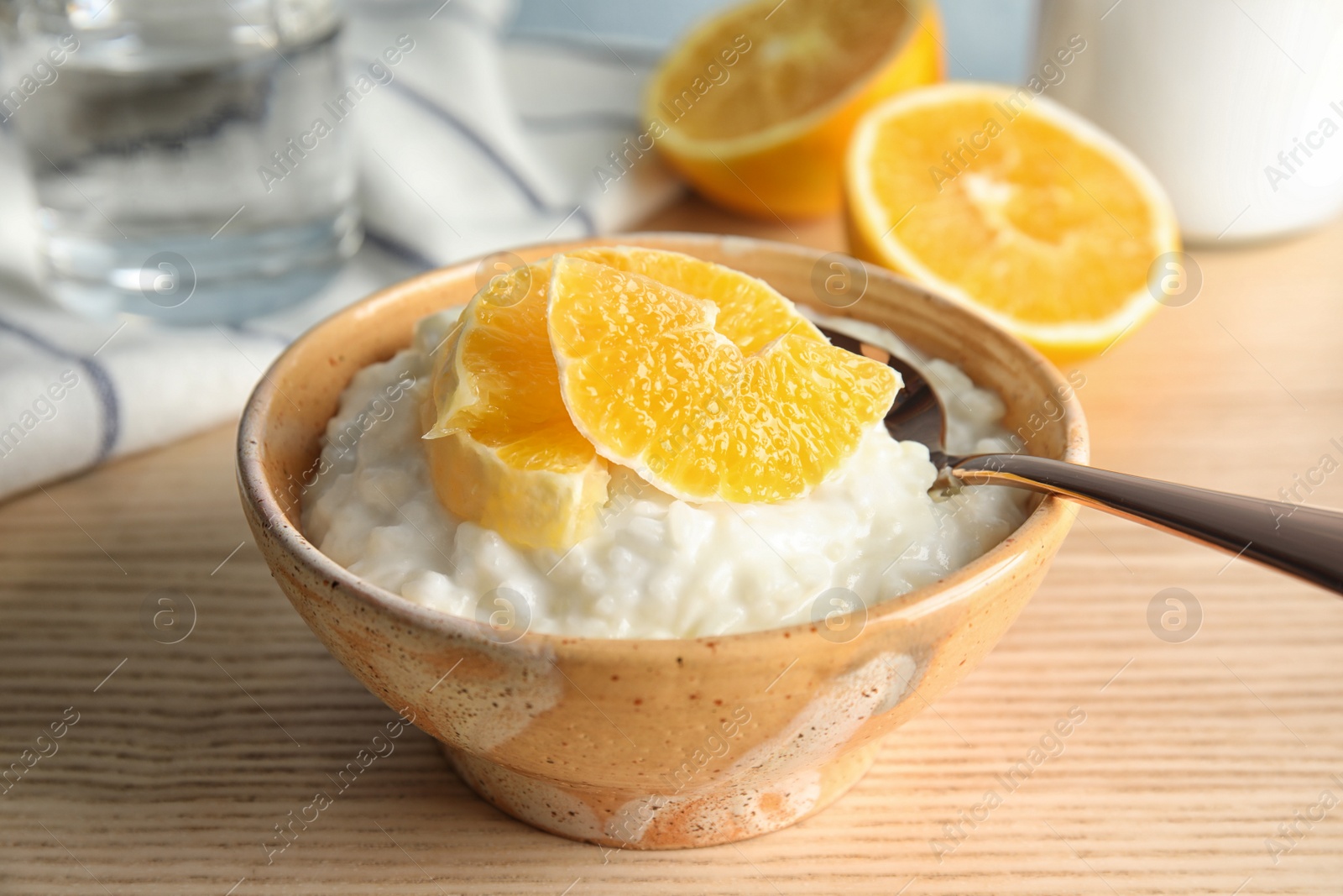 Photo of Creamy rice pudding with orange slices in bowl on wooden table