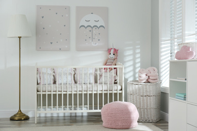 Stylish baby room interior with crib and cute pictures on wall