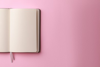 Blank notebook on pale pink background, top view. Space for text