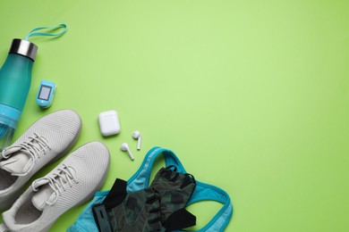 Photo of Flat lay composition with different cycling accessories and clothes on green background, space for text