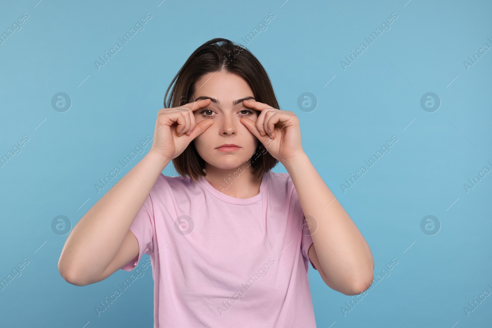 Photo of Sleepy young woman on light blue background. Insomnia problem