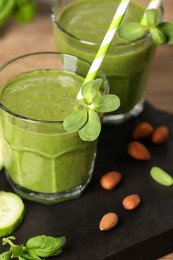 Fresh green smoothie and ingredients on wooden board, closeup