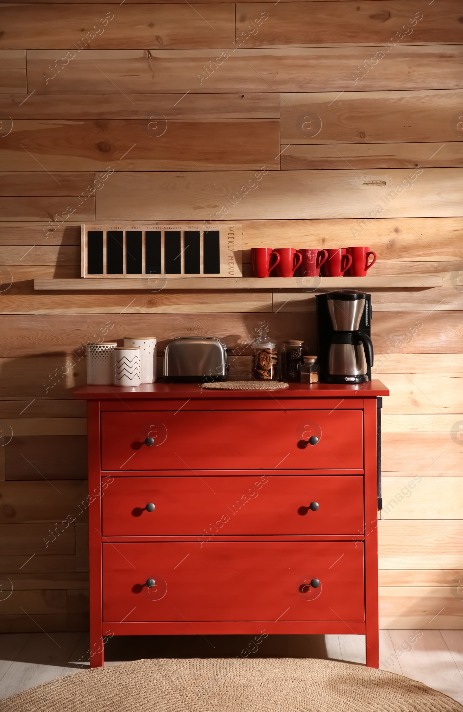 Photo of Stylish room interior with modern coffeemaker and toaster on red chest of drawers