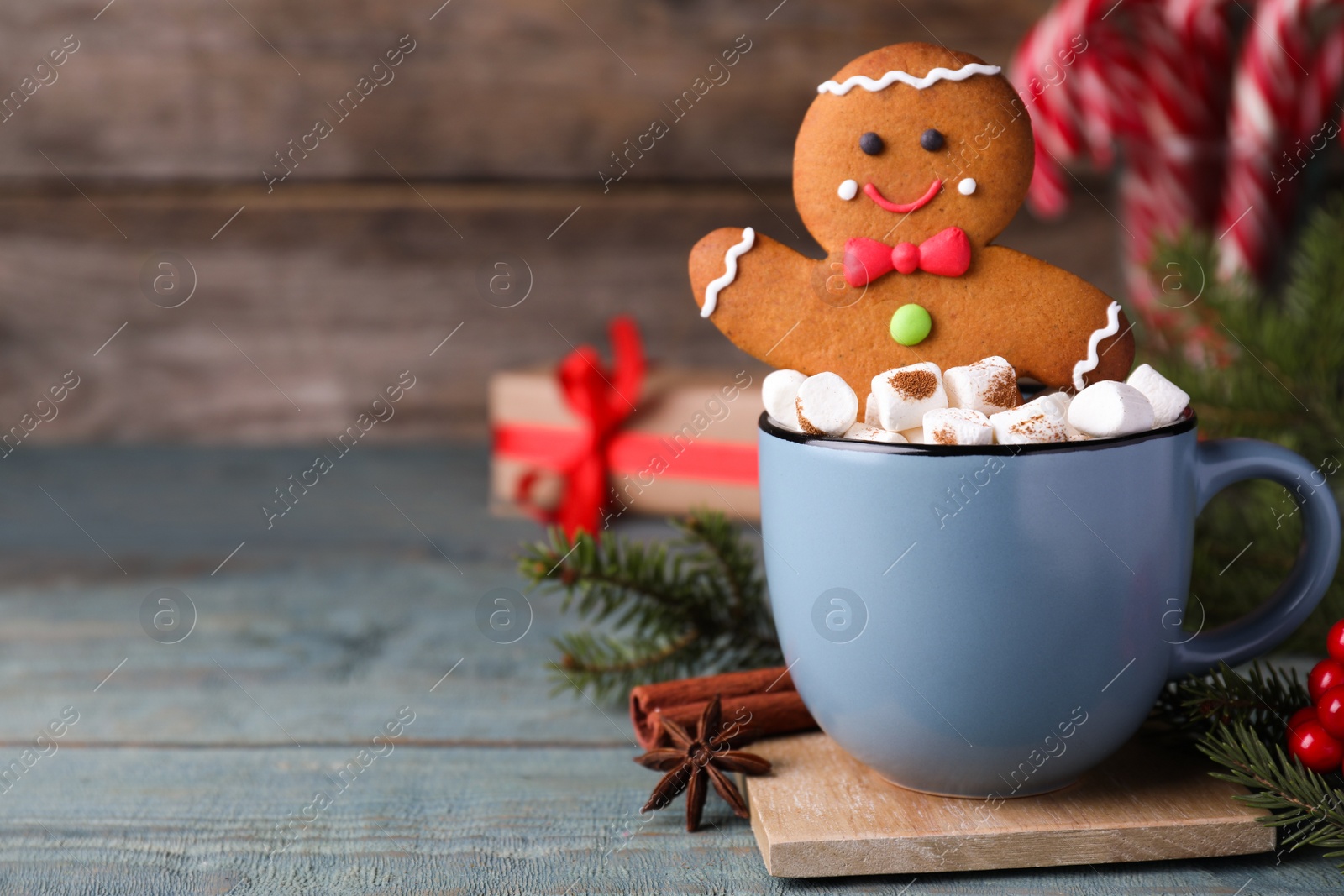 Photo of Gingerbread man in cup on blue wooden table, space for text