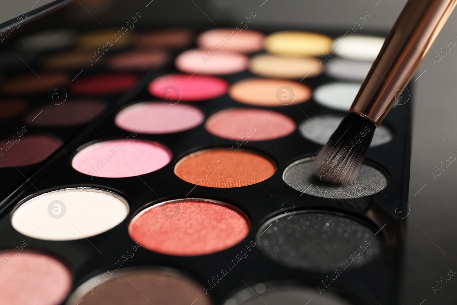 Photo of Colorful eyeshadow palette with brush, closeup view