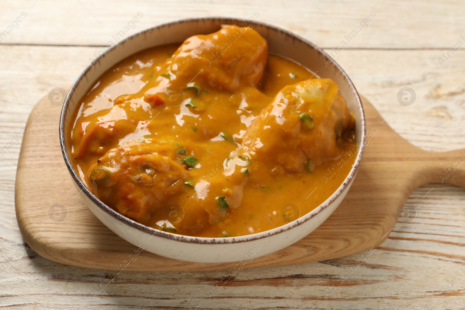 Photo of Tasty chicken curry on wooden table, closeup