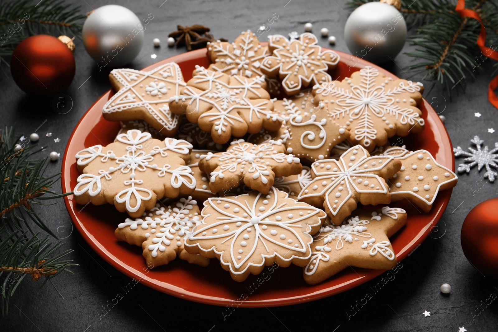 Photo of Tasty Christmas cookies, fir branches and festive decor on black table, closeup