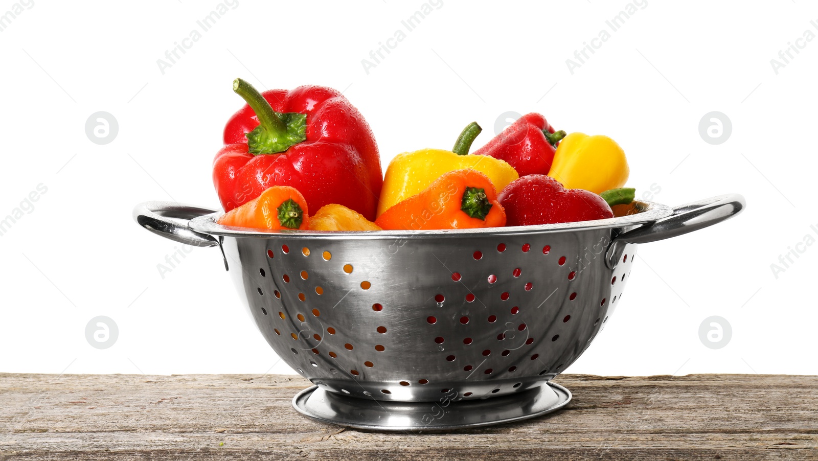 Photo of Metal colander with fresh peppers on wooden table against white background