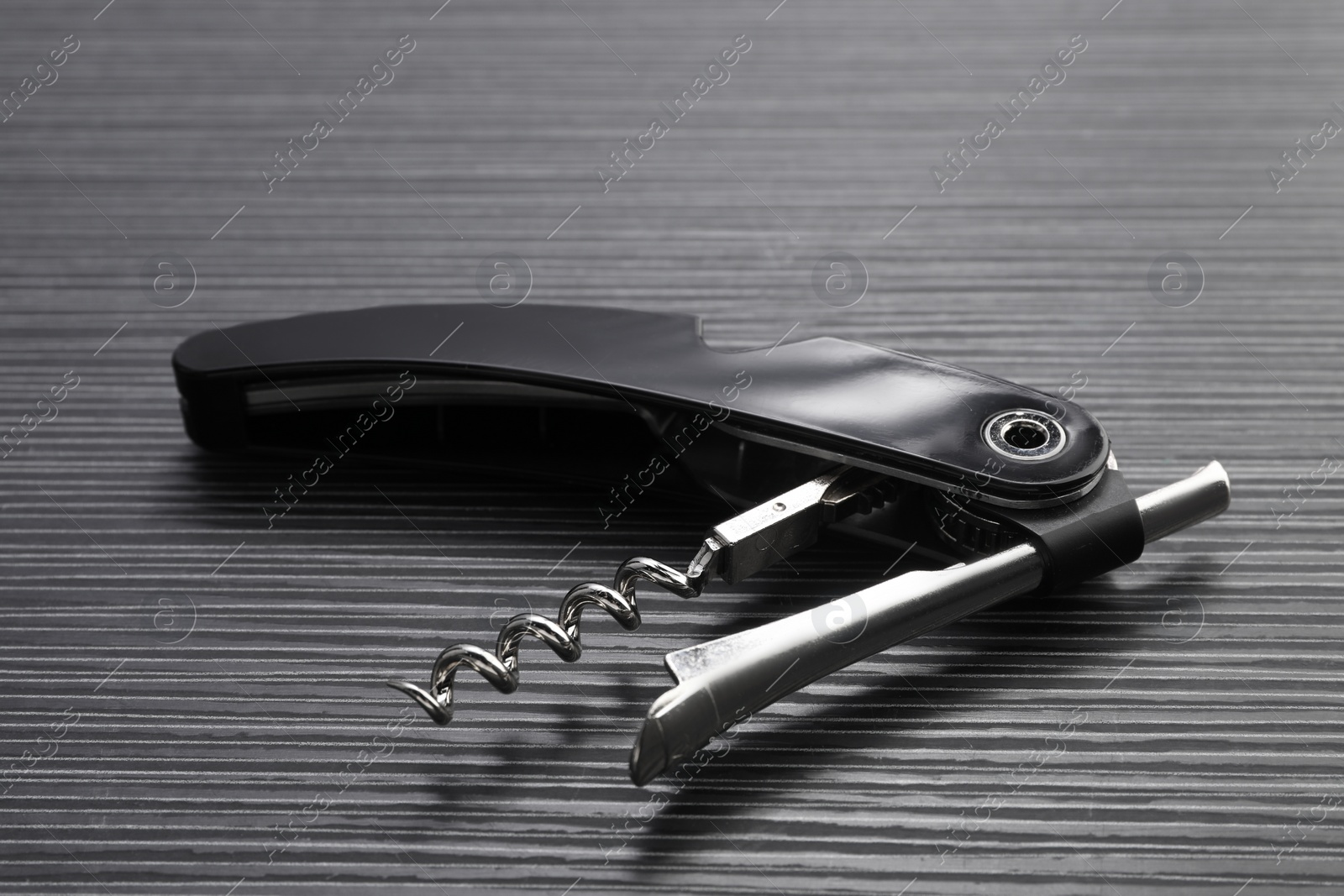 Photo of One corkscrew (sommelier knife) on black wooden table