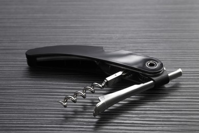 Photo of One corkscrew (sommelier knife) on black wooden table