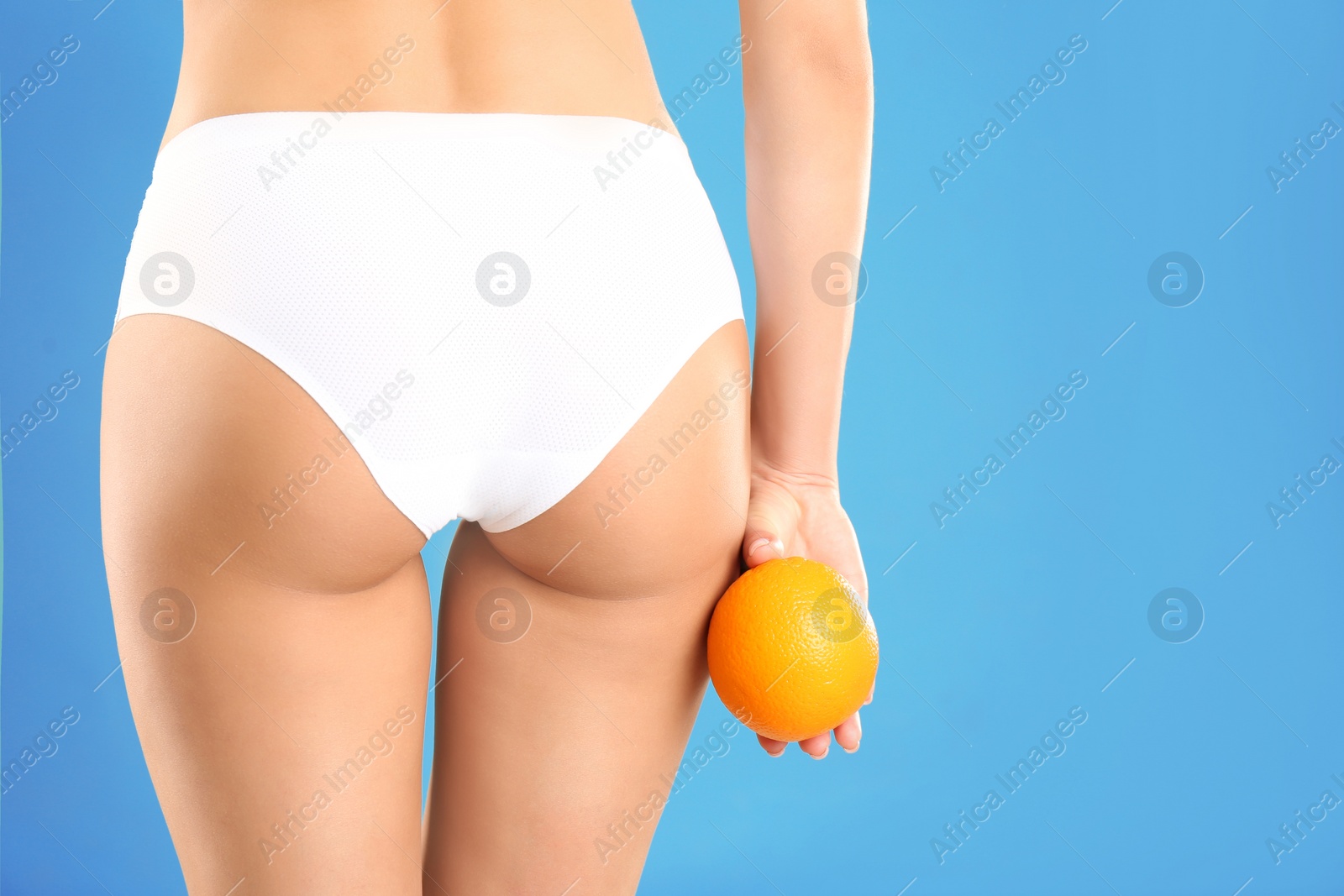 Photo of Closeup view of slim woman in underwear with orange on color background, space for text. Cellulite problem concept