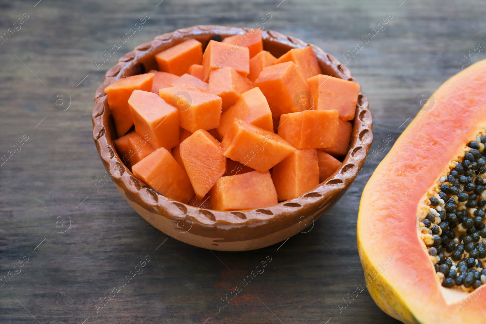 Photo of Tasty ripe cut papaya fruits on wooden table, closeup