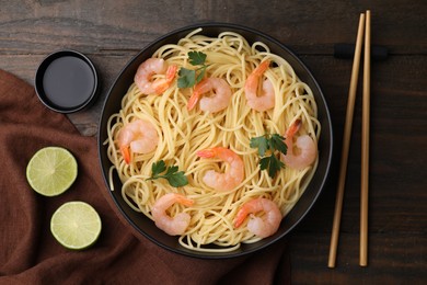 Photo of Tasty spaghetti with shrimps, parsley, lime and soy sauce on wooden table, flat lay