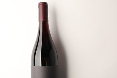 Bottle of tasty red wine on white background, top view. Space for text