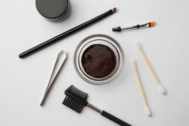 Flat lay composition with eyebrow henna and professional tools on white background