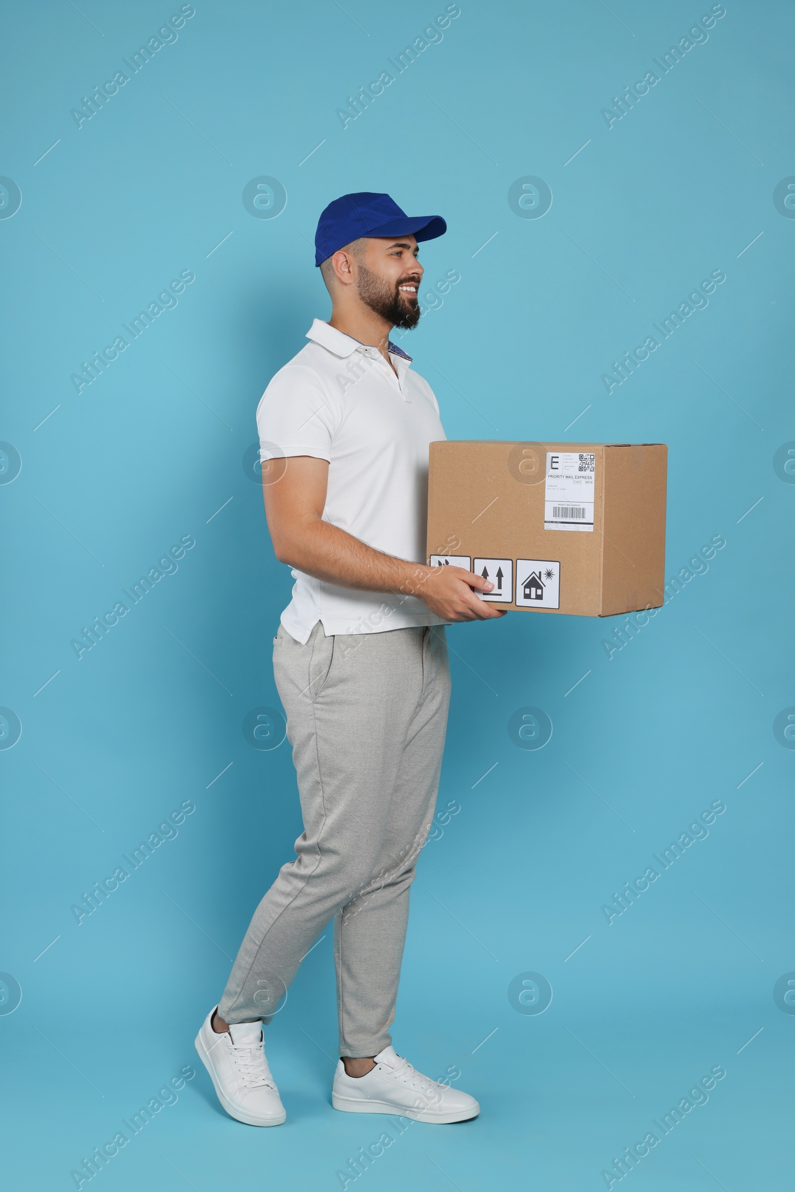 Photo of Courier holding cardboard box on light blue background