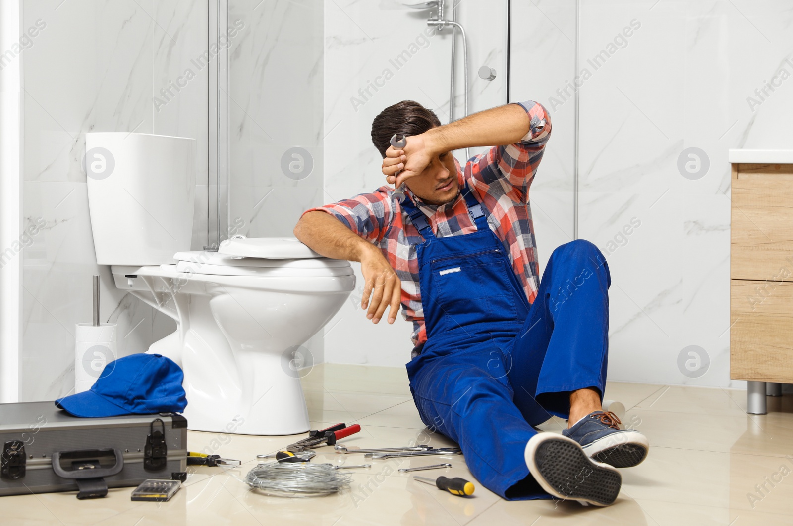 Photo of Professional plumber working with toilet bowl in bathroom