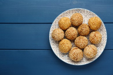 Photo of Delicious sesame balls on blue wooden table, top view. Space for text