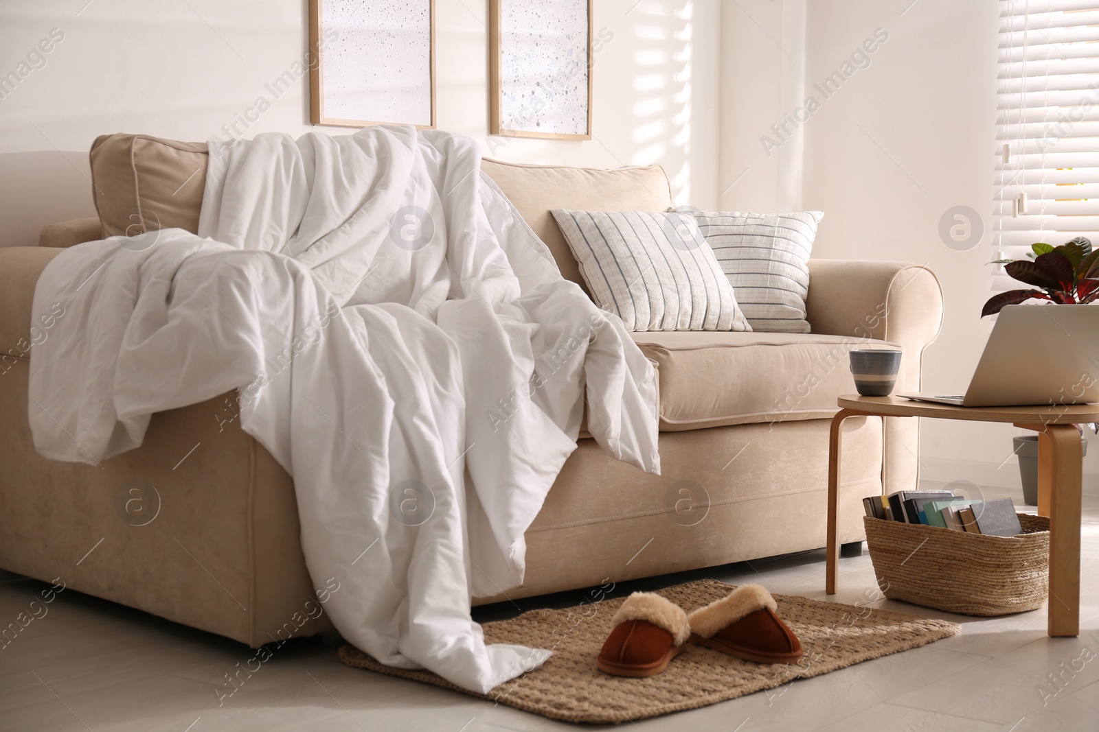 Photo of Comfortable sofa with blanket in stylish room