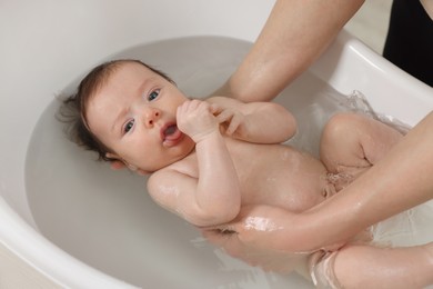 Photo of Mother bathing her little baby in bathtub, closeup