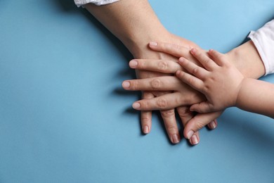 Photo of Family holding hands together on light blue background, top view. Space for text