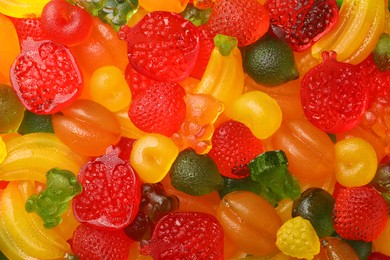 Mix of different delicious gummy candies as background, top view