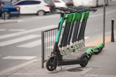 Photo of Many modern electric scooters on city street. Rental service