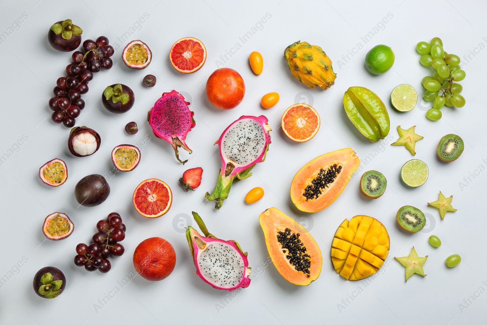 Photo of Many different delicious exotic fruits on light background, flat lay