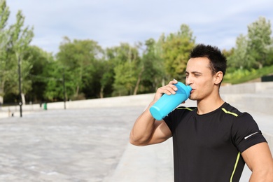 Photo of Young man drinking protein shake on street