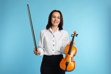 Photo of Music teacher with violin and bow on turquoise background
